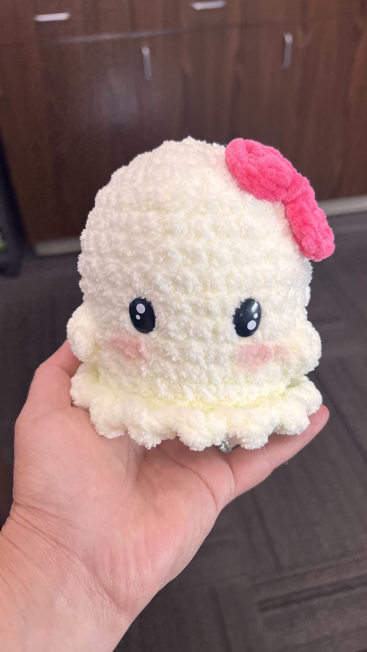 Handmade crochet ghost plushie with a pink bow
